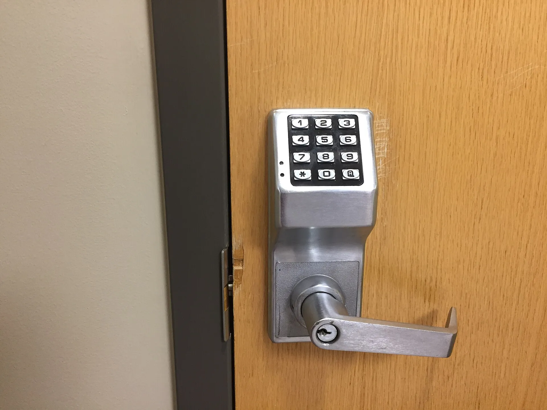 Brushed-steel keypad lever lock with a twelve-key keypad on a wooden door